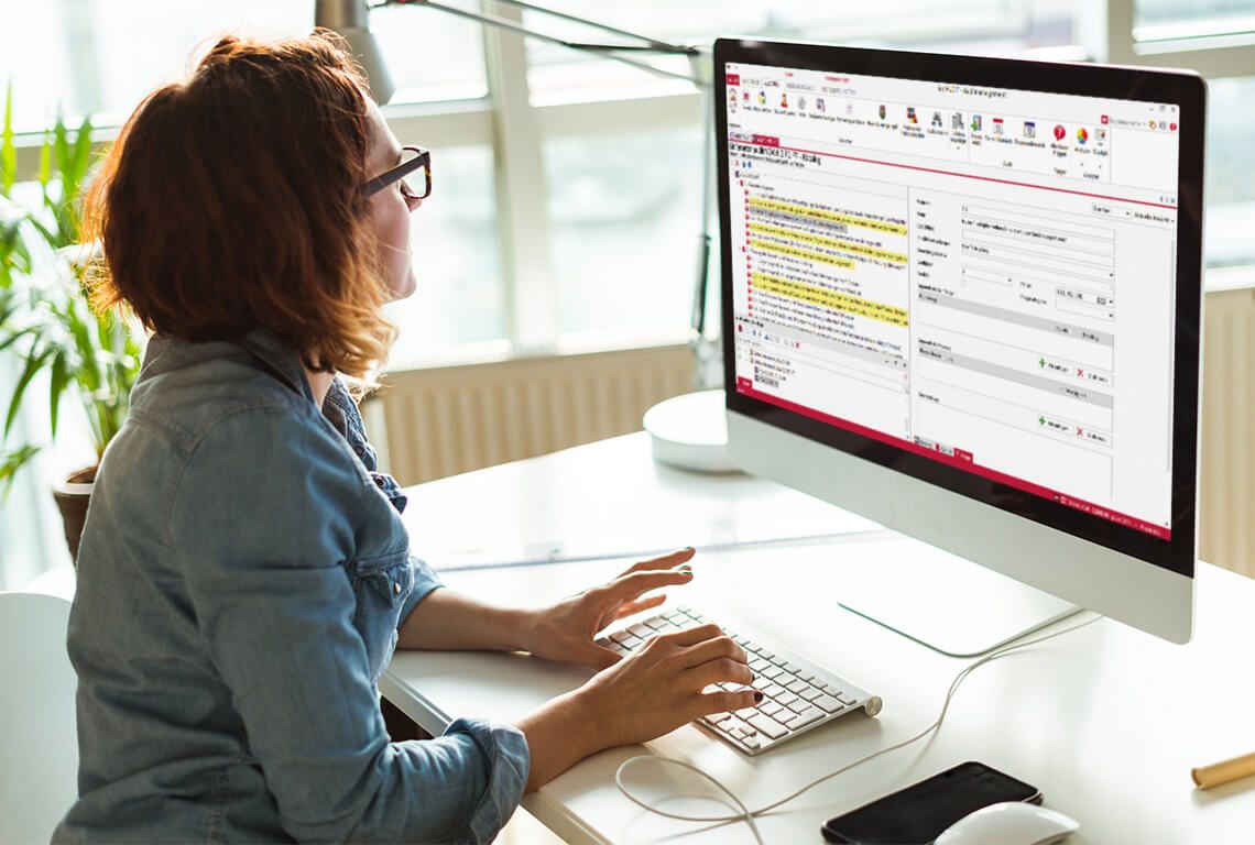 A woman sits in front of a monitor and works through an audit checklist.