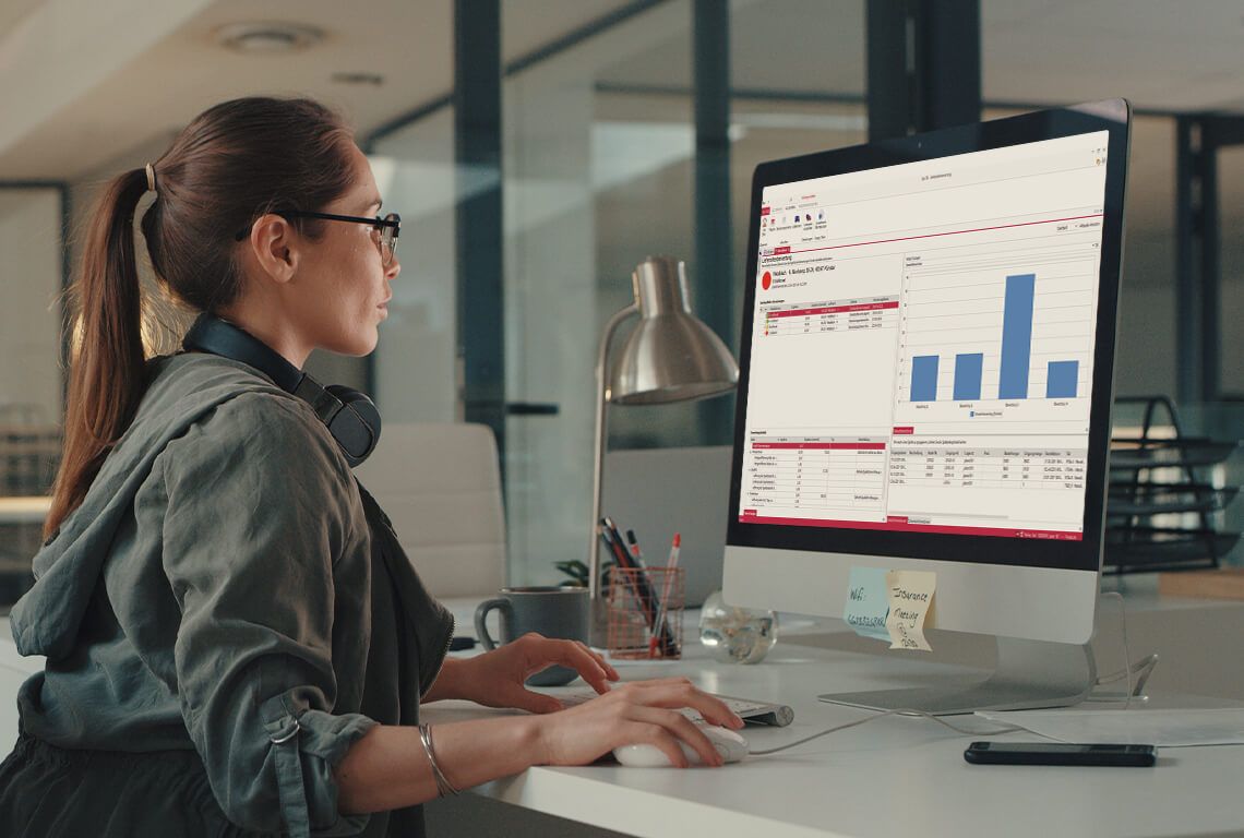 A woman sits in front of a monitor and creates a supplier evaluation