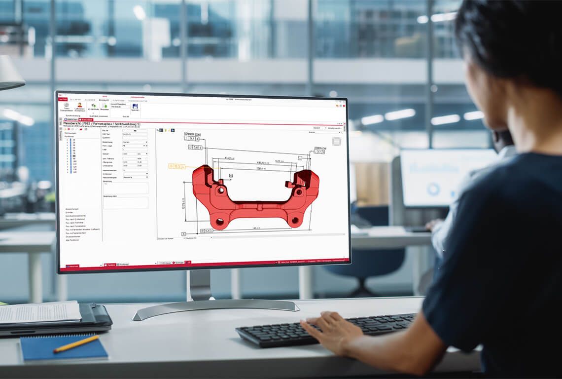 A woman sits in front of a monitor and creates an initial sample inspection report