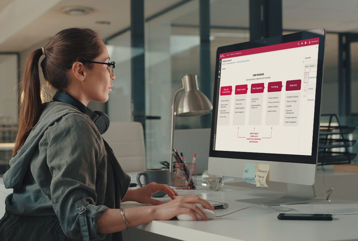 A woman sits in front of a monitor and works on a process map
