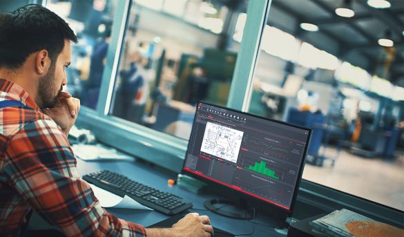 Quality officer sits in front of laptop in production hall and edits list of characteristics