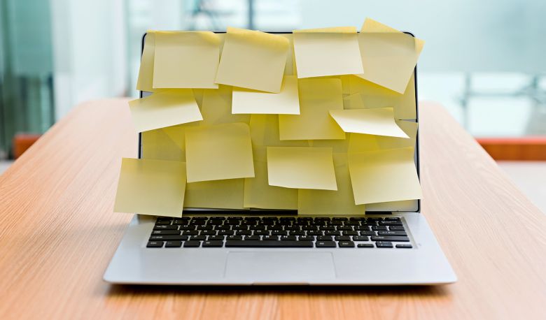 Laptop is on desk and screen is completely covered with yellow sticky notes