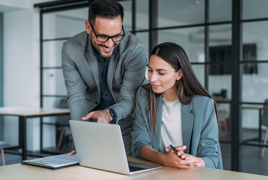 A man and a woman are working together on a laptop.