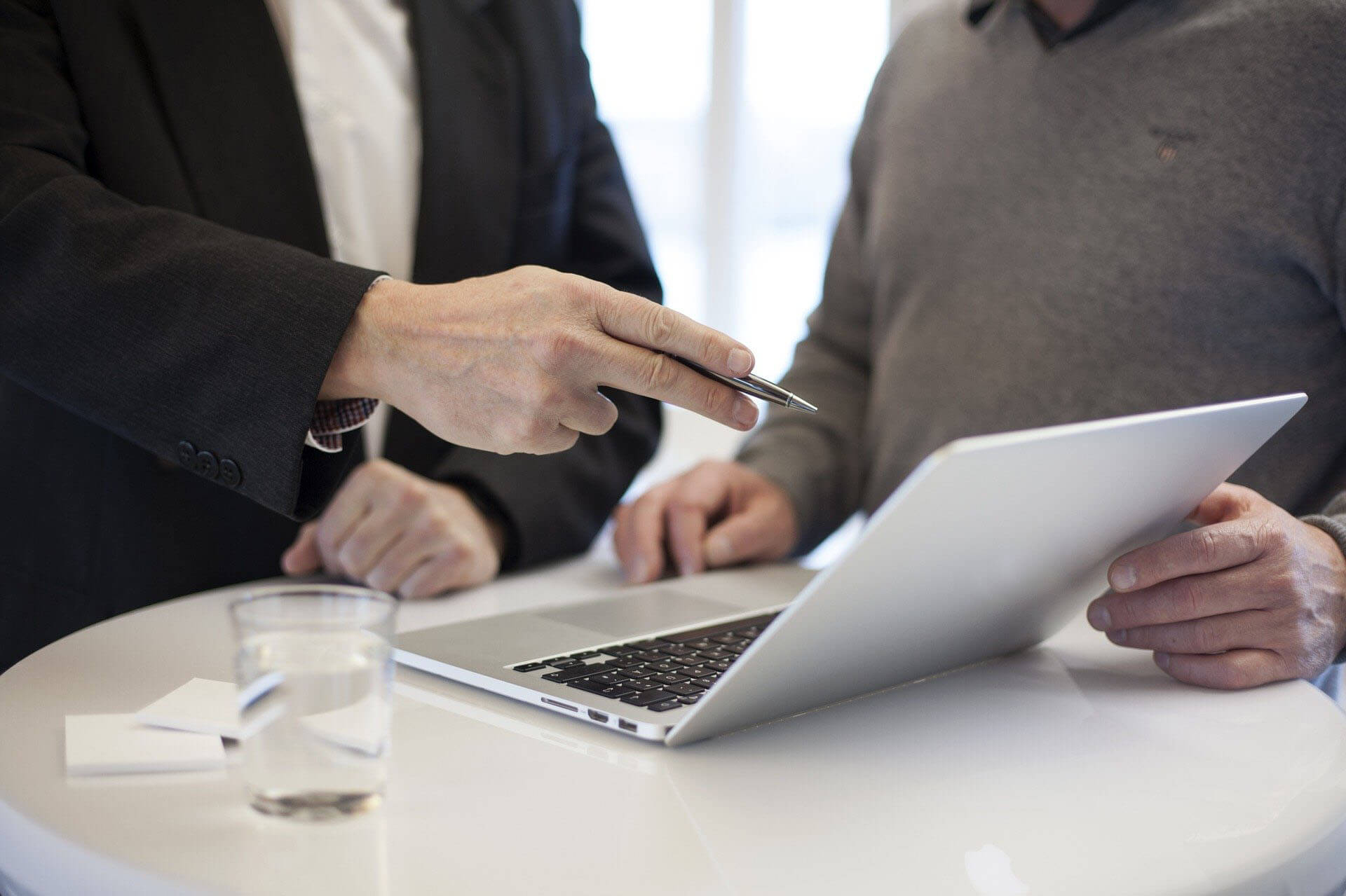 Two people stand in front of a laptop and talk about the content displayed there